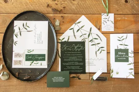 Botanische Hochzeitseinladungen auf Glas. Grüner Zweig auf dem Hintergrund von Flaschengrün