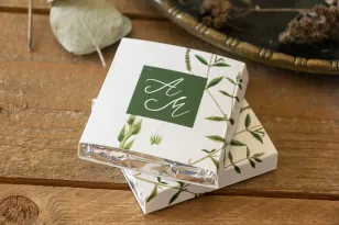 Danke an die Hochzeitsgäste in Form von Milchschokolade, Deckblatt mit grünem Zweig vor flaschengrünem Hintergrund