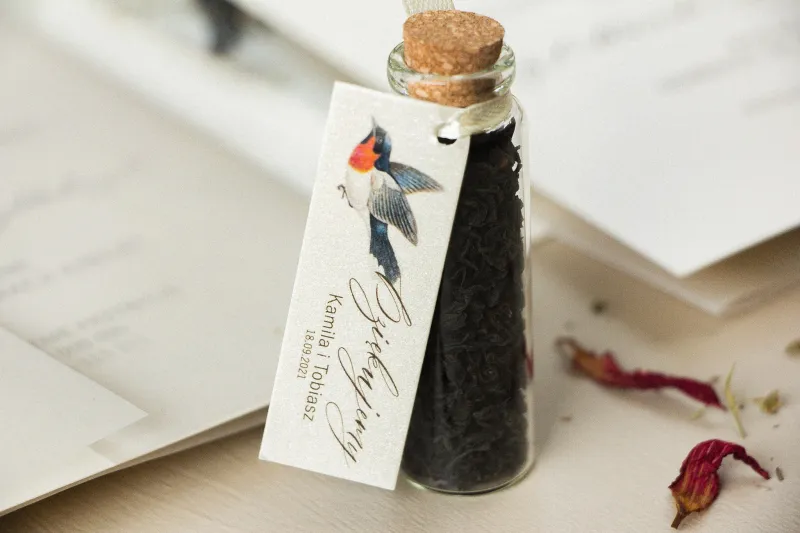 Podziękowania dla Gości w postaci buteleczek z herbatą, przywieszka na perłowym papierze z grafiką ptaków w stylu vintage
