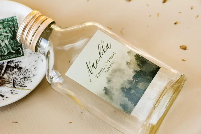 Szklane butelki z grafiką leśną na etykiecie | Upominki ślubne dla gości