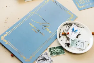 Menu weselne ze złoceniem w stylu Glamour w kolorze dusty blue z kaligrafinczą, złotą czcionką.