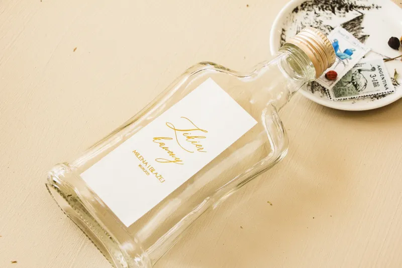Hochzeitsflaschen für Tinkturen, Geschenke für Gäste. Minimalistisches Etikett in weißer Farbe mit Vergoldung