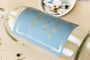 Etykiety samoprzylepne na butelki weselne na alkohol w kolorze dusty blue z kaligrafinczą, złotą czcionką