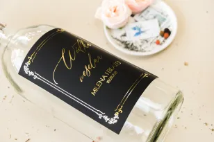 Czarne Etykiety samoprzylepne na butelki weselne na alkohol w stylu glamour ze złotym tekstem oraz złotą ramką