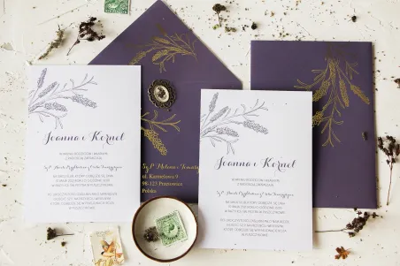 Hochzeitseinladungen mit Lavendelmotiv. Die Einladungen werden von einem eleganten lila Umschlag mit goldenen Lavendelzweigen be