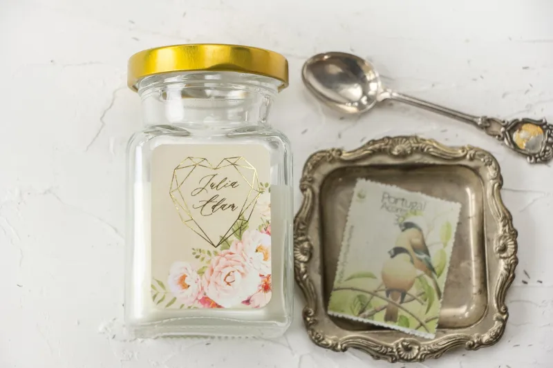 Świeczki Ślubne jako podziękowania dla gości. Kremowa etykieta ze złoceniami i z bukietem pastelowych kwiatów