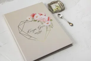 Cremiges Hochzeitsgästebuch mit Vergoldung und einem Strauß pastellfarbener Blumen.