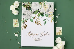 Hochzeitsgästebuch mit vergoldeten Zweigen und einem Strauß weißer Pfingstrosen und Hortensien und einem goldenen Taufbecken