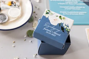 Eine Schachtel für Süßigkeiten für Hochzeitsgäste in Form eines Würfels mit weißen Pfingstrosen und Rosen