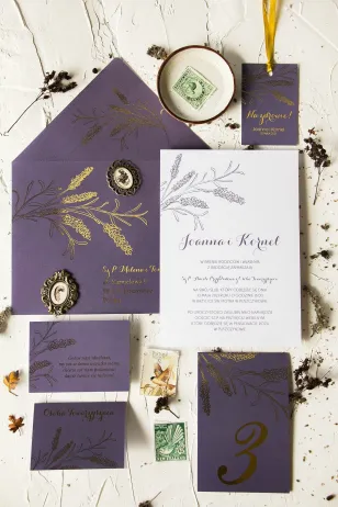 Hochzeitseinladungen mit Lavendelmotiv. Die Einladungen werden von einem eleganten lila Umschlag mit goldenen Lavendelzweigen be