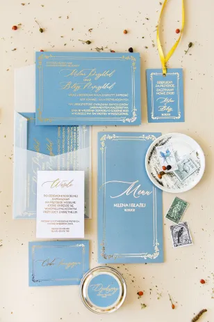 Elegante Hochzeitseinladungen mit vergoldetem Rahmen. Hochzeitseinladung in staubigem Blau mit Kalligraphie