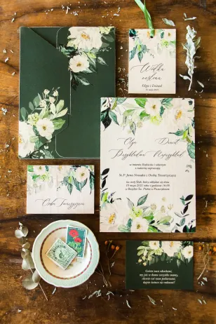 Hochzeitseinladungen auf Holz. Einladungen in flaschengrüner Farbe mit dem Zusatz von weißen Blumen und dekorativen Zweigen