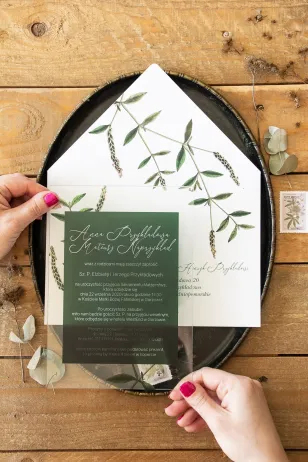 Botanische Hochzeitseinladungen auf Glas. Grüner Zweig auf dem Hintergrund von Flaschengrün
