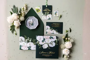 Zaproszenia ślubne w kolorze butelkowej zieleni z eleganckim bukietem z białych róż i piwonii
