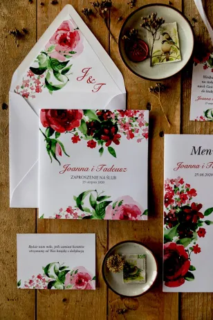 Hochzeitseinladungen mit burgunderfarbenen Blüten kombiniert mit grünen Blättern. Umschlag in sanftem Grau