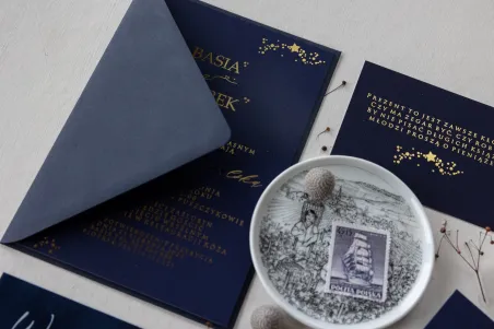 Marineblaue Hochzeitseinladungen mit vergoldeten Sternen. Den Einladungen wird ein marineblauer Umschlag beigefügt
