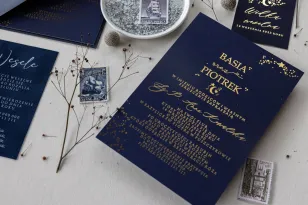 Granatowe zaproszenia ślubne ze złoconymi gwiazdkami. Do zaproszeń dodana jest granatowa koperta