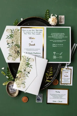 Goldene Hochzeitseinladungen mit weißen Hortensien und Tulpen umgeben von viel Grün