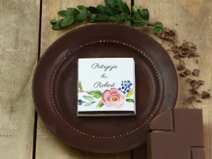 Podziękowanie dla gości weselnych w postaci mlecznej czekoladki, owijka z grafiką róż i gałązek w barwach zieleni i chabru