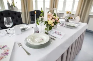 Stół weselny z zaproszeniami ślubnymi, dodatkami weselnymi. Białe i różowe piwonie oraz bez