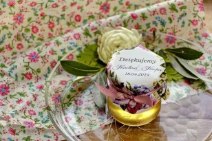 Süße Geschenke für Hochzeitsgäste in Form von Gläsern mit Honig. Eindrucksvolle Komposition aus Rosen- und Fliederblüten