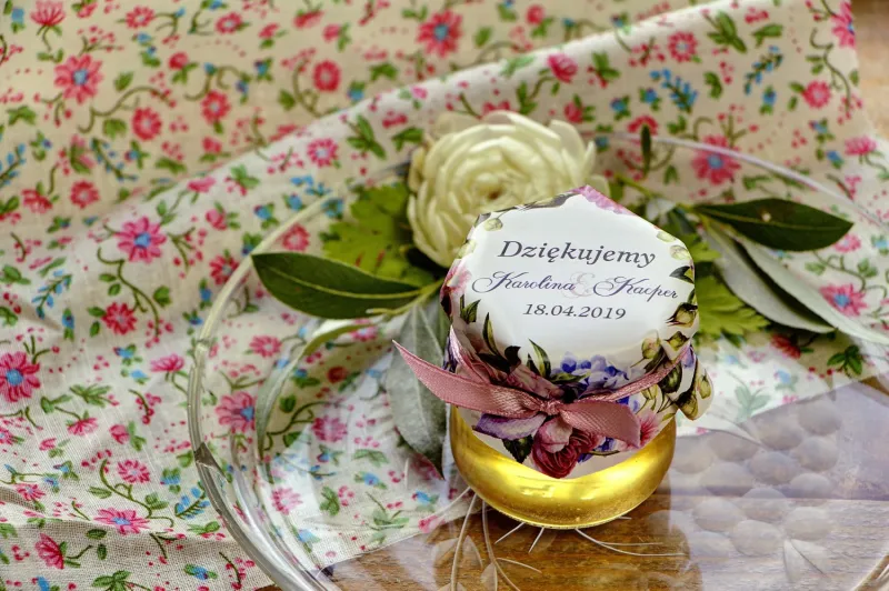 Słodkie upominki dla gości weselnych, ślubnych w postaci słoiczków z Miodem. Efektowna kompozycja kwiatów róży i bzu