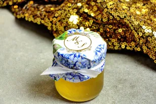Ein Glas mit Honig - ein süßes Dankeschön für die Hochzeitsgäste. Kapuze mit vergoldeten Initialen. Blaue Hortensie.