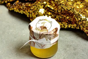 Ein Glas mit Honig - ein süßes Dankeschön für die Hochzeitsgäste. Kapuze mit vergoldeten Initialen. Zarte Federn im Boho-Stil