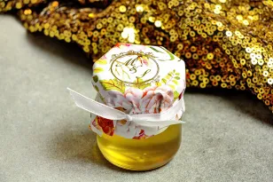 Glas Honig - ein süßes Dankeschön an die Hochzeitsgäste. Mütze mit vergoldeten Initialen. Zusammensetzung von Pfingstrose und Ro