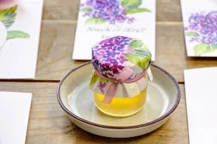 Süßes Dankeschön an die Hochzeitsgäste in Form von Gläsern mit Honig. Frühling, intensive lila Fliederblüten