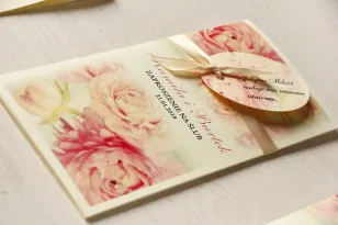 Kremowe zaproszenia ślubne z piwonią w pastelowym odcieniu jasnego różu. Całość przewiązana ozdobną przywieszką z wierszykiem.