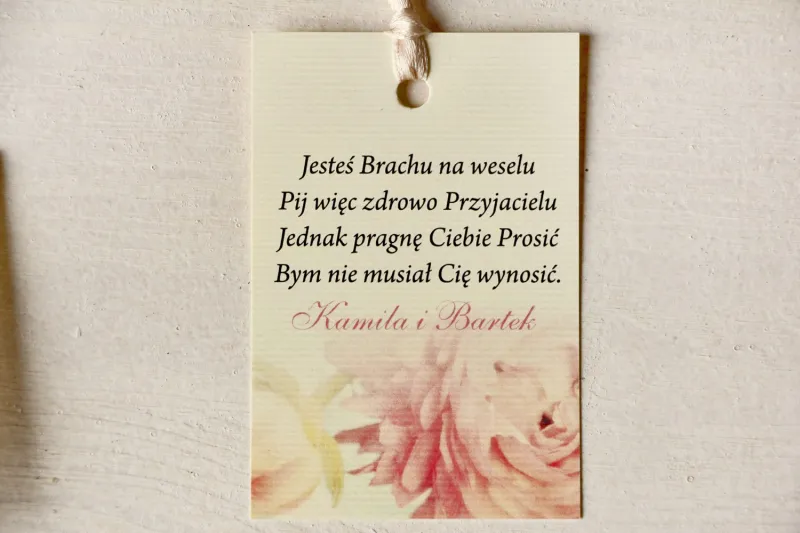 Kremowe zawieszki na butelki weselne z piwonią w pastelowym odcieniu jasnego różu. Kremowe zawieszki na butelki weselne z piwonią w pastelowym odcieniu jasnego różu.