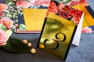 Złocone numery stolików weselnych, granatowa grafika z różowymi piwoniami i różami z dodatkiem zielonych liści