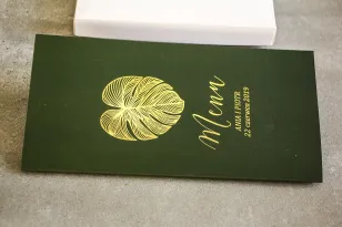 Vergoldetes Glamour-Hochzeitsmenü. Eine elegante Kombination aus Grün und vergoldeten Monstera-Blättern