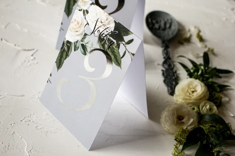 Numery stolików weselnych z białymi różami w stylu glamour ze srebrnym tekstem
