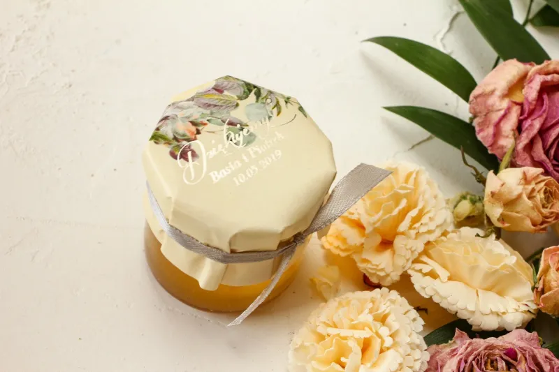 Ein Glas Honig dank der Hochzeitsgäste. Cremefarbene Kapuze im Glamour-Stil mit Vintage-Blumenstrauß Ein Glas Honig dank der Hochzeitsgäste. Cremefarbene Kapuze im Glamour-Stil mit Vintage-Blumenstrauß