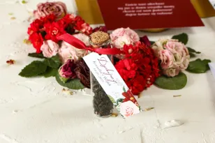 Podziękowania dla Gości w postaci buteleczek z herbatą, przywieszka z bordowymi daliami i pastelowymi różami