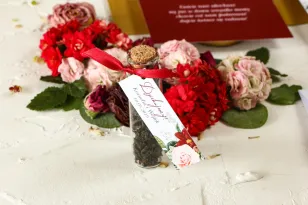 Dank der Gäste in Form von Teeflaschen, einem Anhänger mit burgunderroten Dahlien und pastellfarbenen Rosen