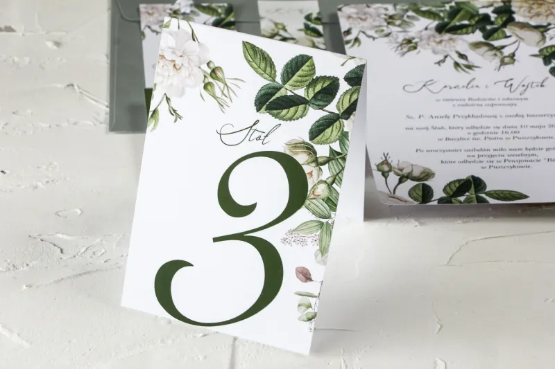 Zielone Numery stolików weselnych z białymi różami i delikatnymi zielonymi gałązkami