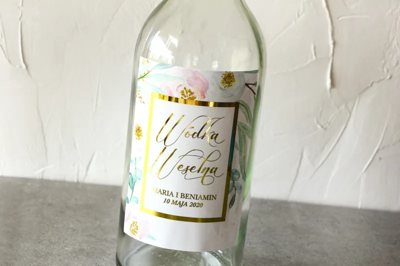 Etykiety samoprzylepne na butelki weselne ze złoconą ramką. Subtelny wzór z różowymi i białymi piwoniami