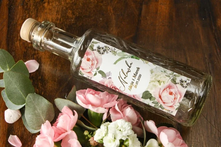Ekskluzywne butelki na nalewki z delikatnymi różami i białą hortensją ze złoceniem | Upominki dla gości weselnych