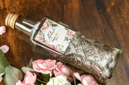 Ekskluzywne butelki na nalewki z delikatnymi różami i białą hortensją ze złoceniem | Upominki dla gości weselnych