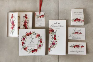Ein Set Hochzeitseinladungen in einer Schachtel mit weinroten Rosen und Feldgras