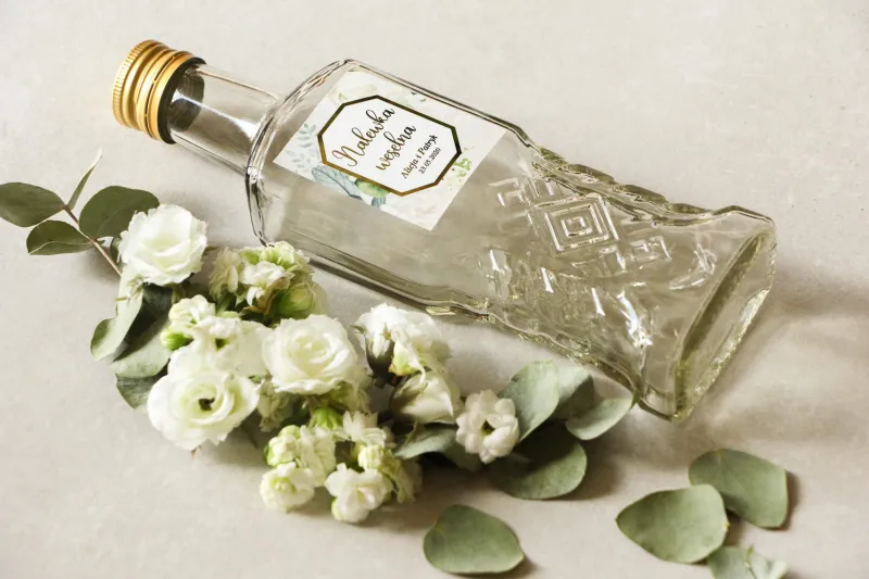 Butelki na nalewki wraz z etykietą w stylu glamour z białymi różami i piwoniami