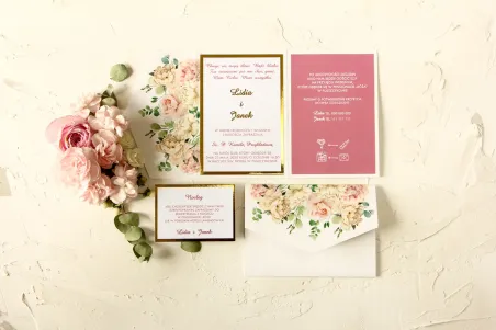 Złote zaproszenia ślubne z różowymi piwoniami w towarzystwie białych róż i zieleni