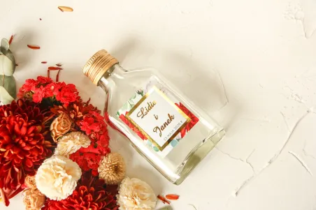 Butelki na nalewki wraz ze złoconą etykietą oraz z bordowymi i białymi różami