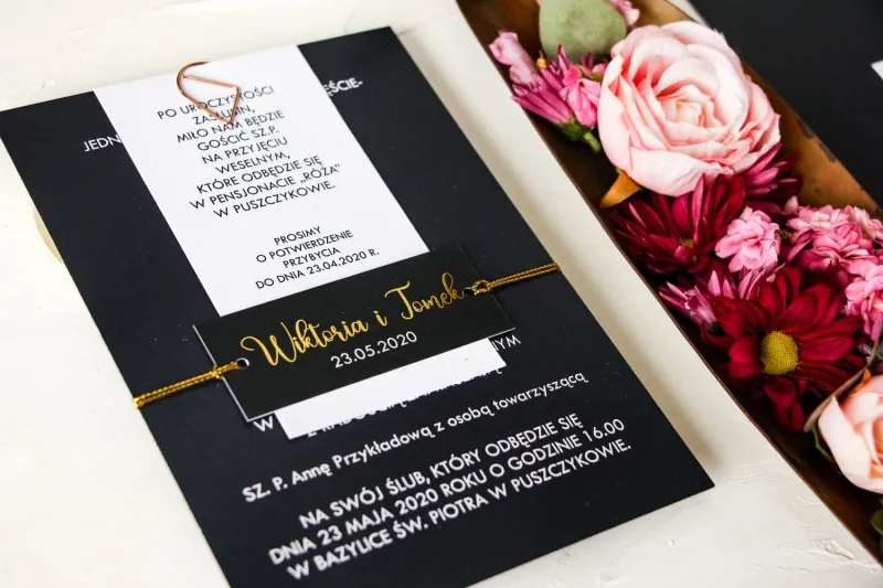 Granatowe zaproszenia ślubne w nowoczesnym stylu. Zaproszenia przewiązane bilecikiem ze złotą czcionką