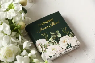 Hochzeitspralinen als Dankeschön an die Gäste. Vergoldetes Deckblatt mit einem eleganten Bouquet aus weißen Rosen und Pfingstros