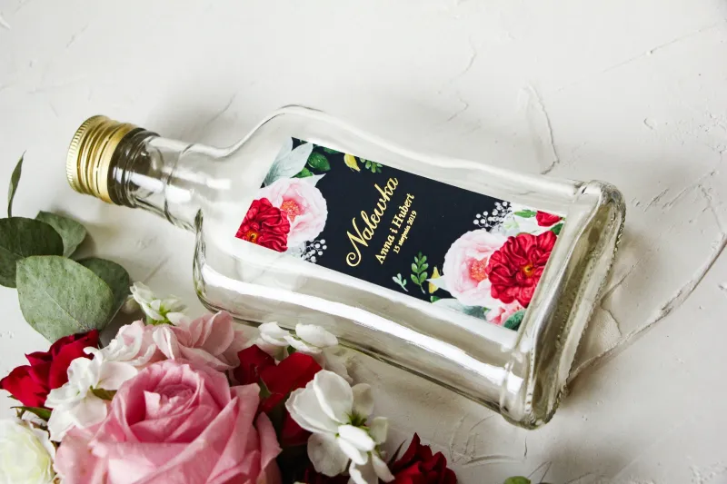 Ślubne Butelki na nalewki wraz ze złoconą etykietą oraz z eleganckim bukietem z różowych piwonii, róż i białego zawilca Ślubne Butelki na nalewki wraz ze złoconą etykietą oraz z eleganckim bukietem z różowych piwonii, róż i białego zawilca