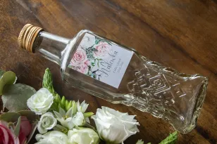 Hochzeitstinkturflaschen mit grauem Etikett mit einer Komposition aus weißen und pastellfarbenen Rosen